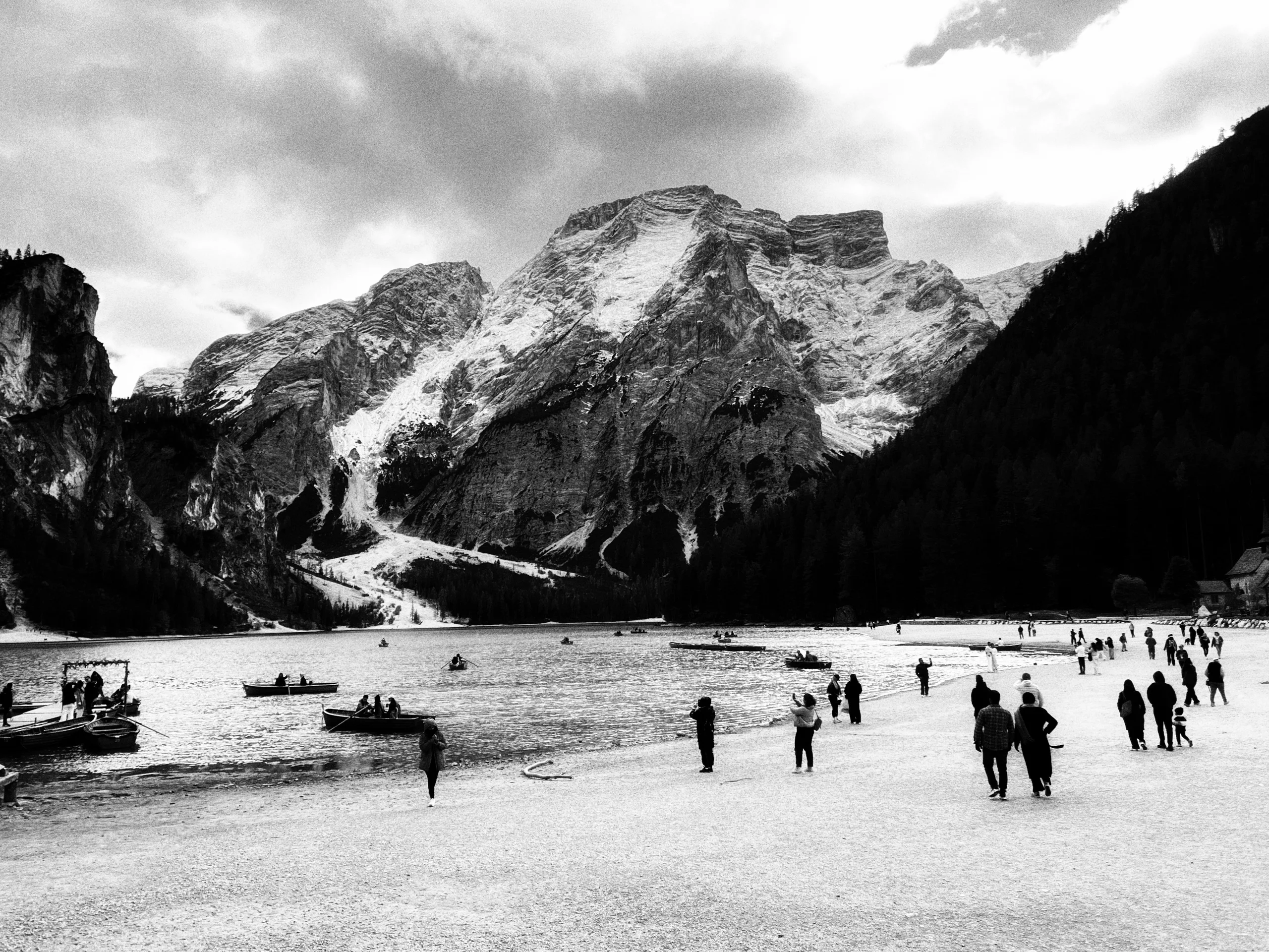 Black and white frame: a mountain lake, boats and people on the shore