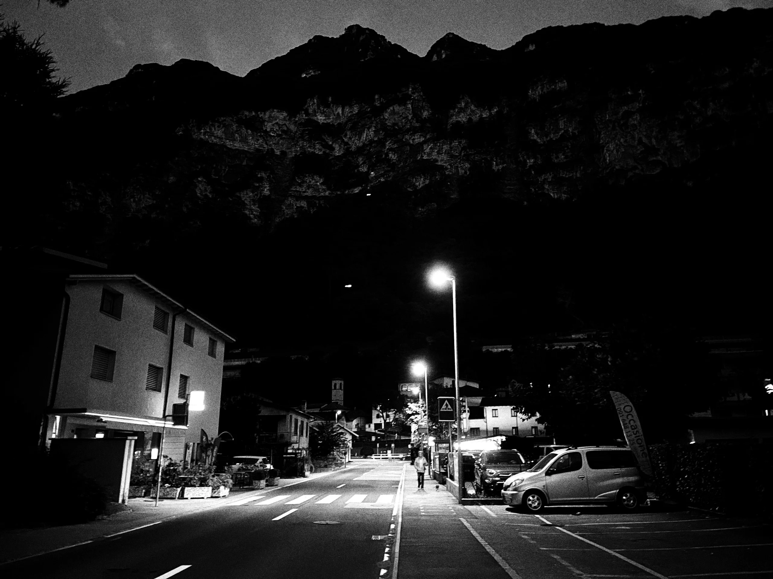 Night street with streetlights and mountains behind, black and white