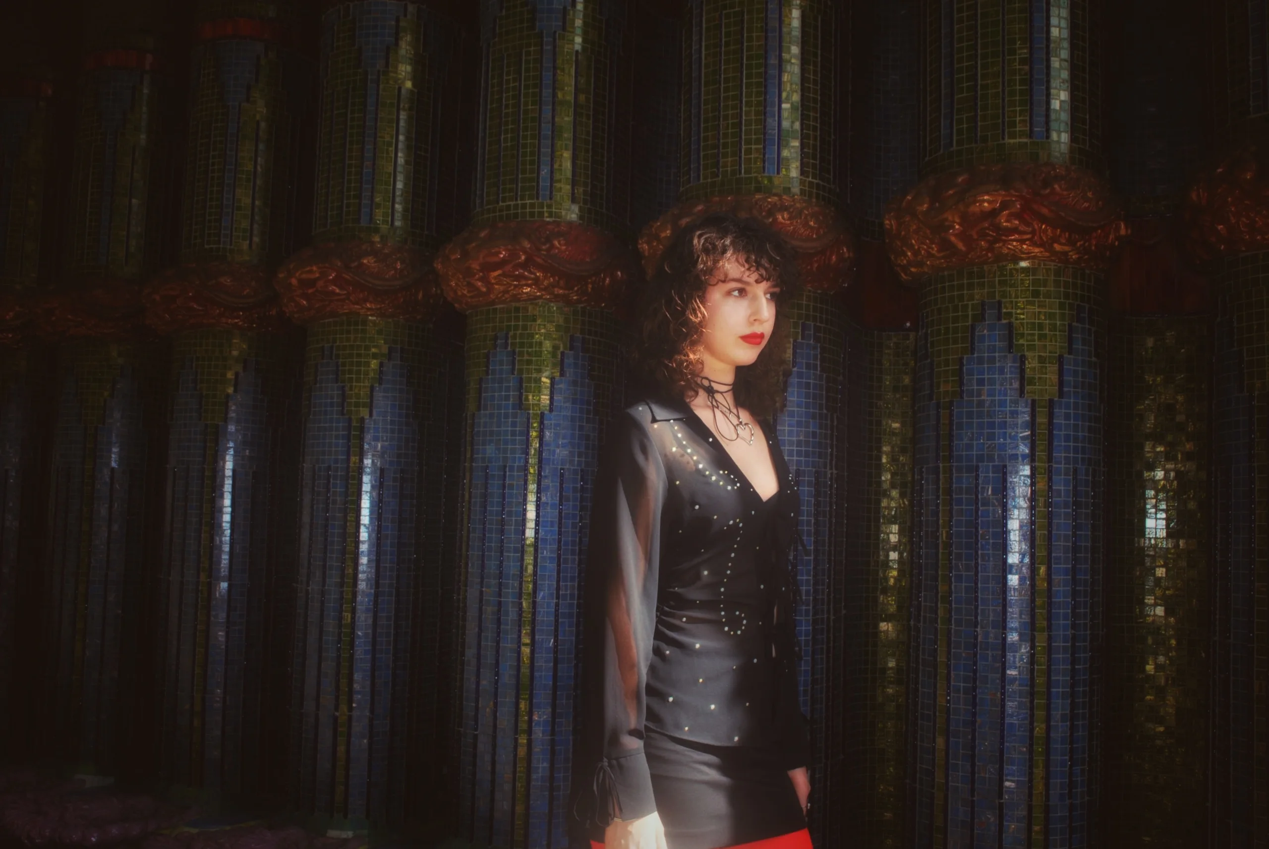 Model in black against blue mosaic columns with red ornament, Otto Wagner Villa