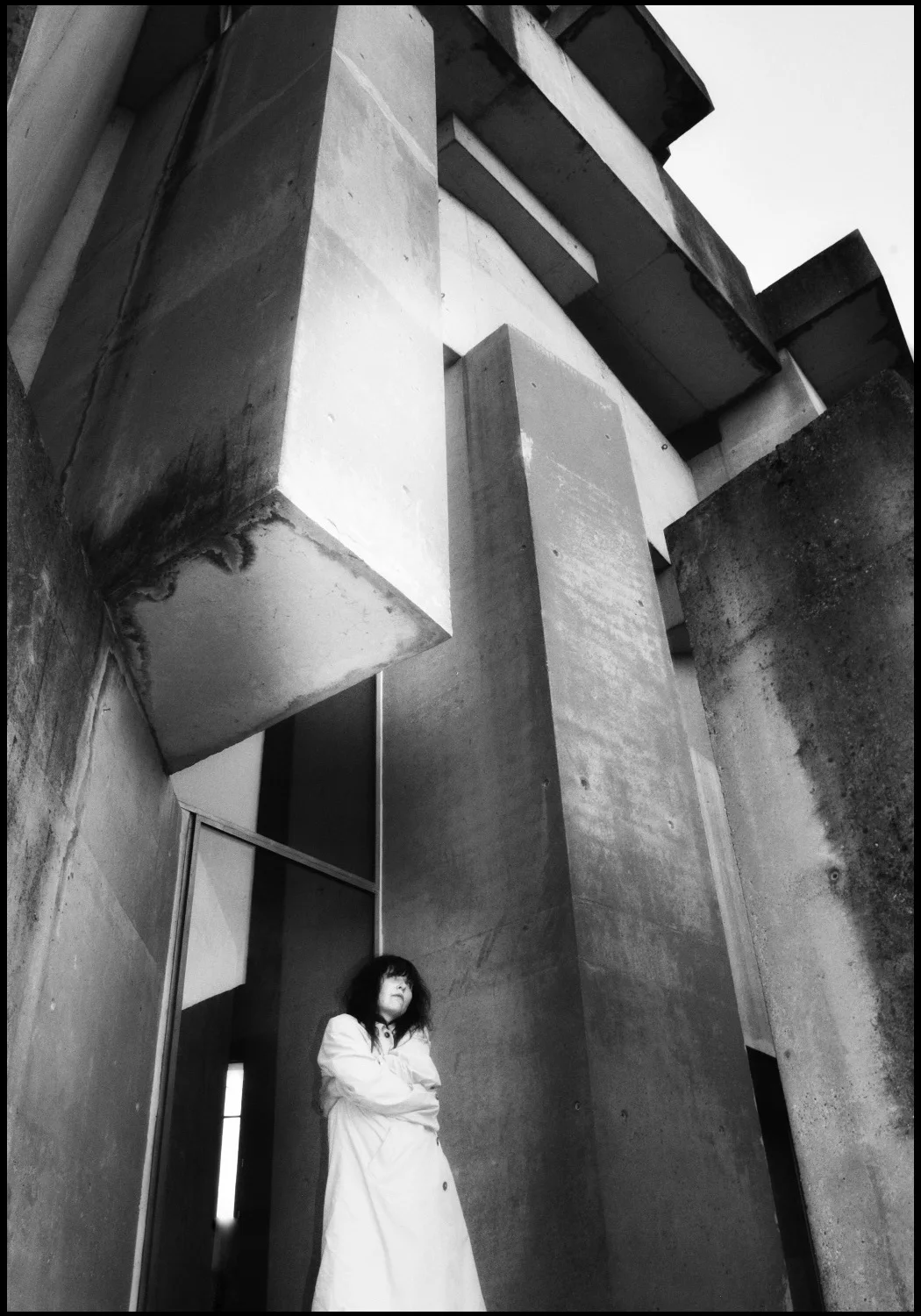 Black and white frame: concrete blocks of the Wotruba Church and a figure in a light coat
